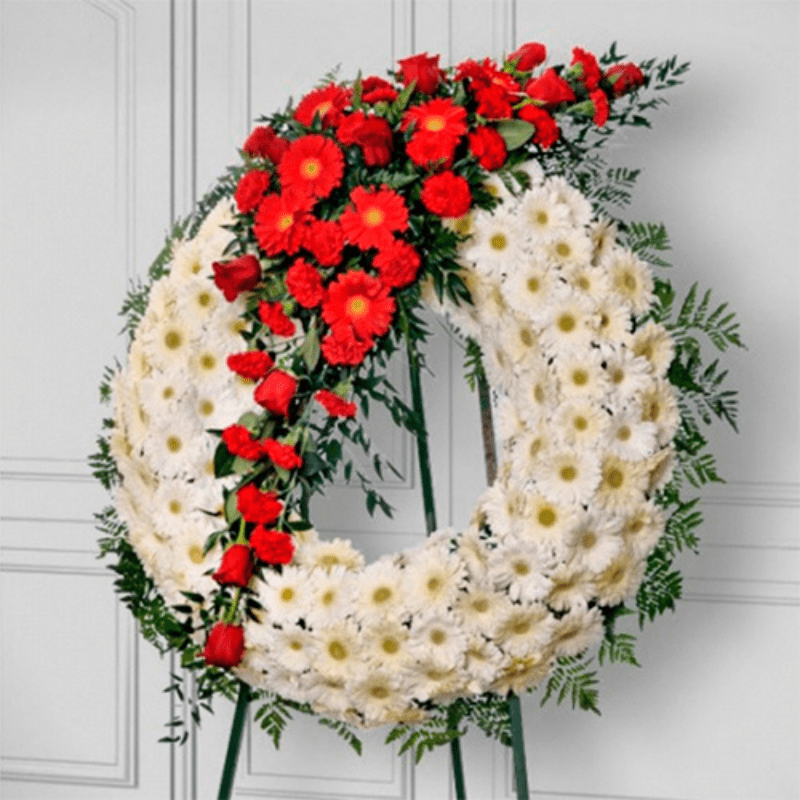 corona funebre con flores blancas y rojas