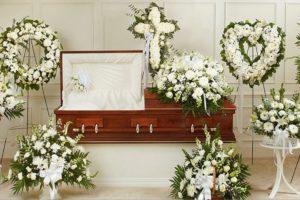arreglos florales blancos sobre un ataud cafe