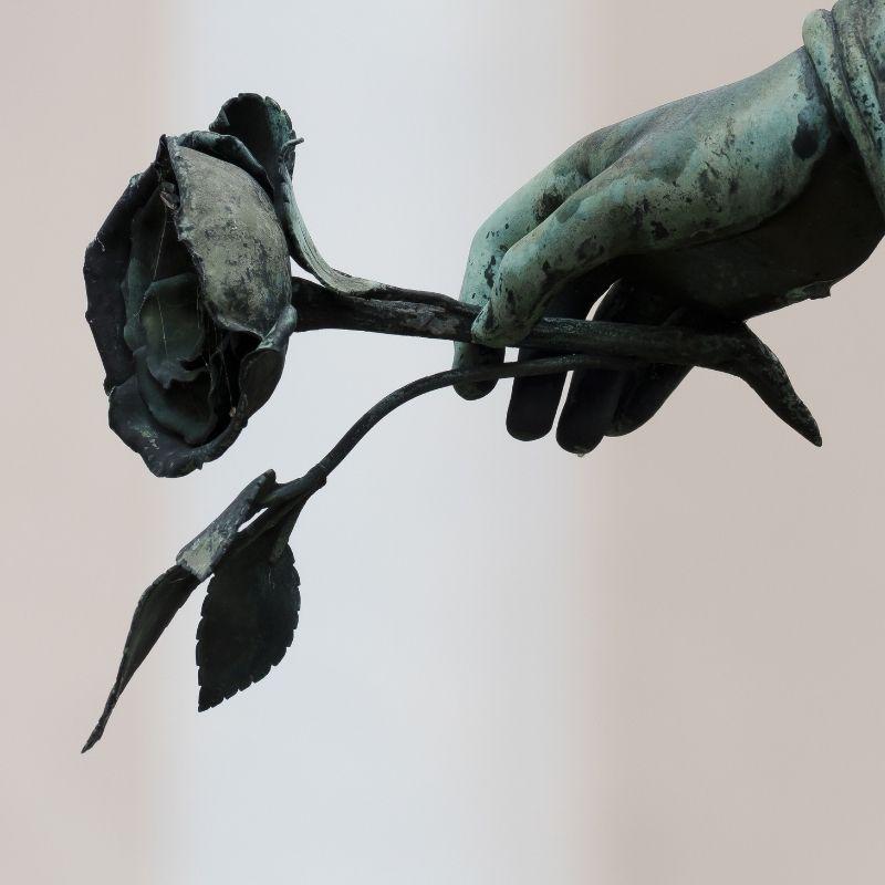 mano con guantes negros agarrando una flor negra